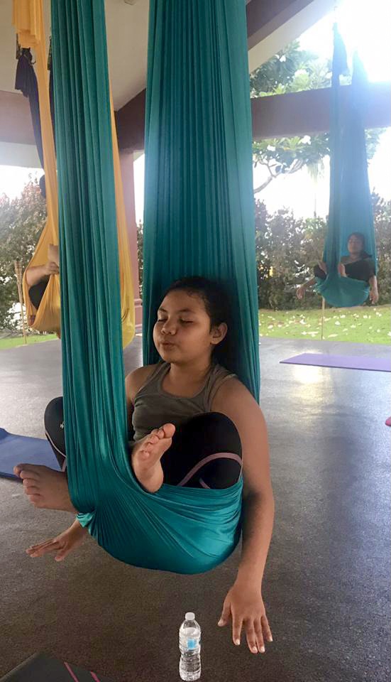 Student meditating in a teal silk cocoon